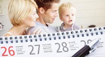 Familie mit einem kleinen Kind schaut auf einen Wandkalender, der die Tage 26, 27 und 28 zeigt.